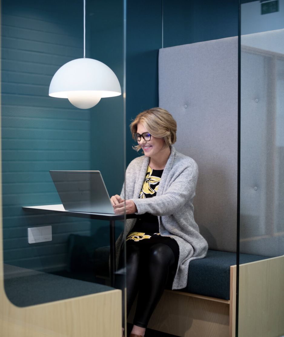 Kvinne i bås som sitter på laptopen sin