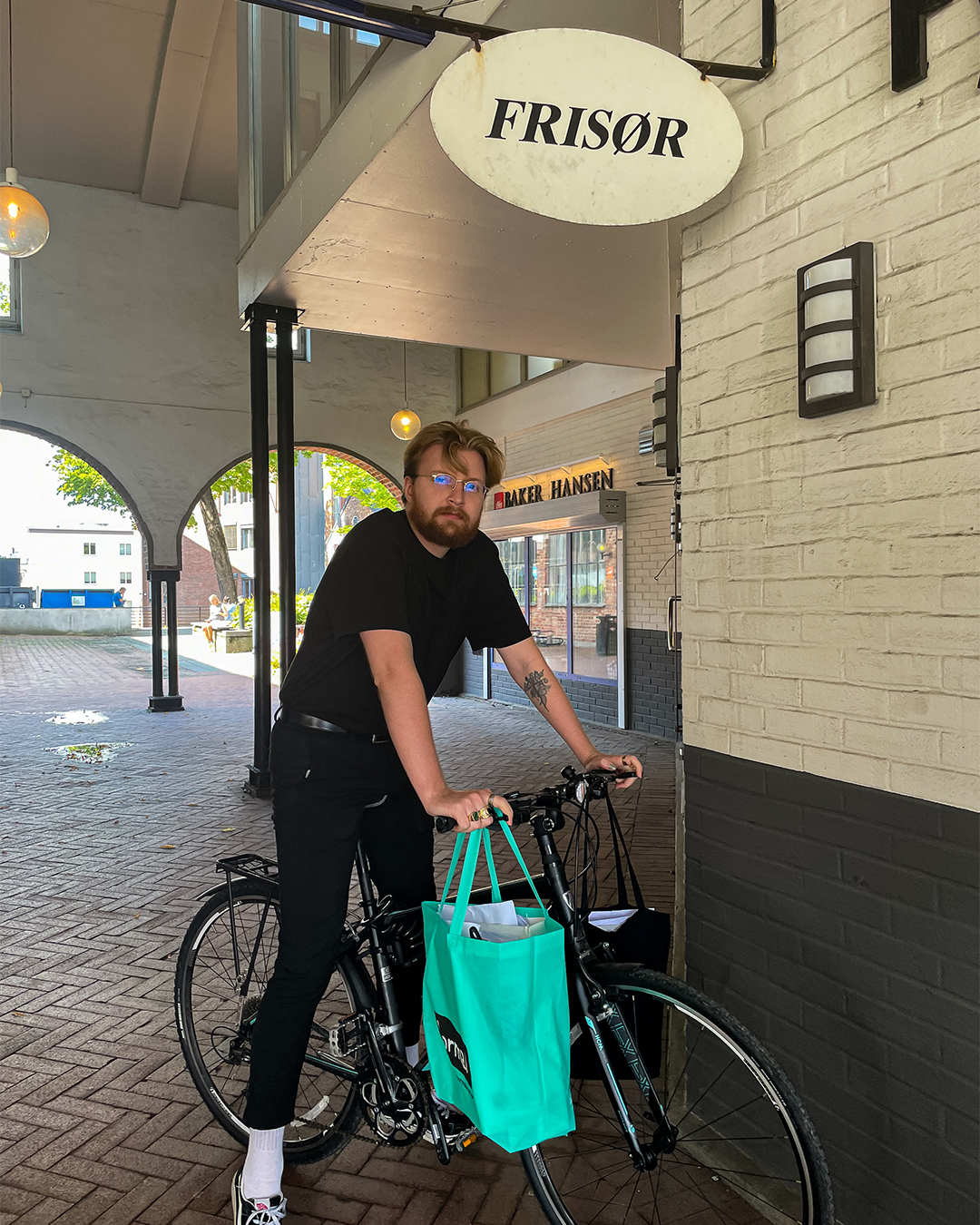 Frisør som står på en sykkel med bilag på styret