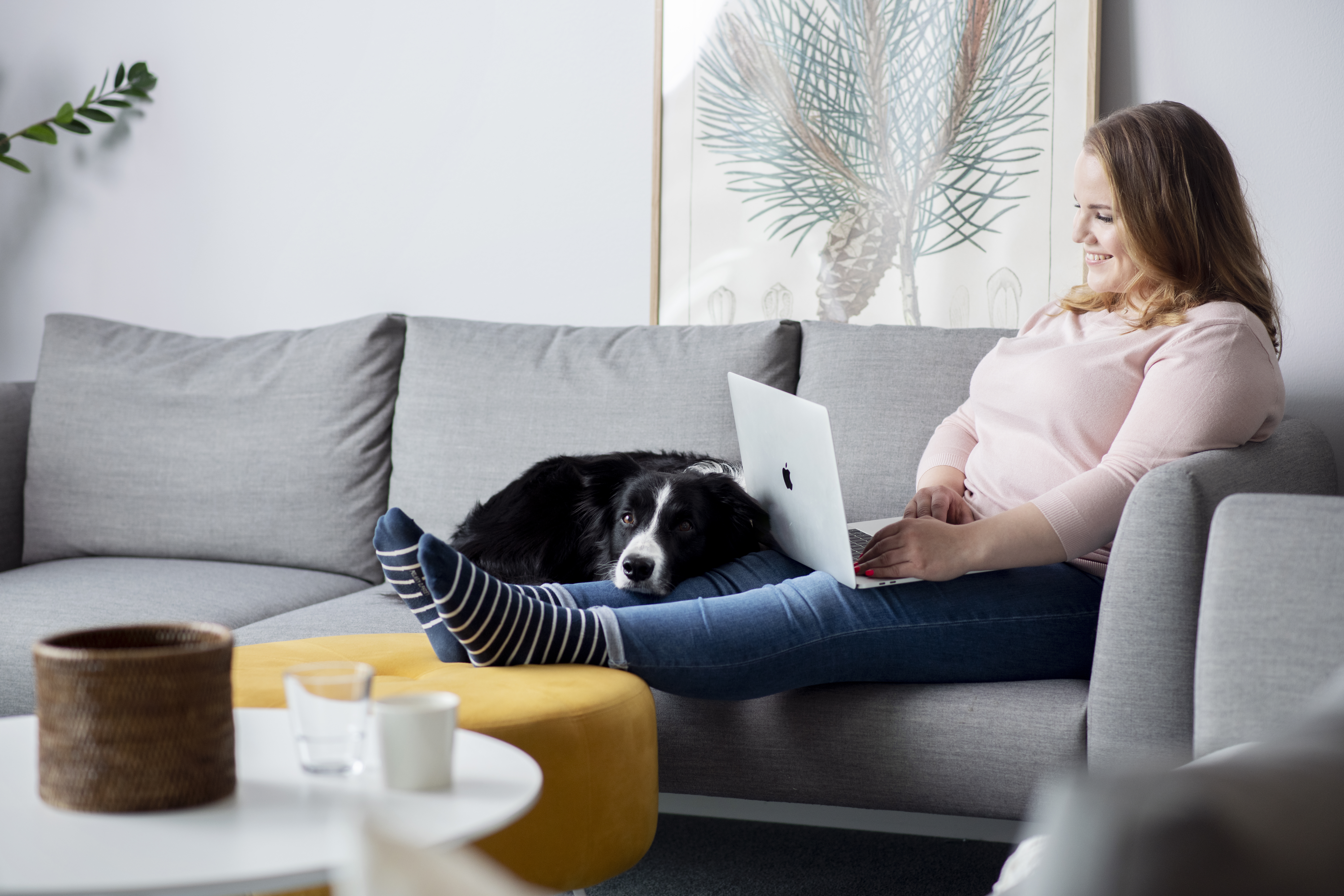 Kvinne som sitter i sofaen og jobber hjemmefra