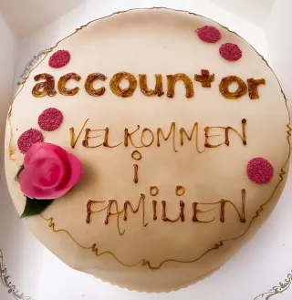 Marsipankake med skrift og en rød/rosa rose: Accountor - velkommen til familien