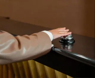 Hånd som plinger i bjelle på resepsjonsdisken