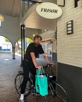 Frisør som står på en sykkel med bilag på styret