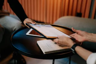 person-in-black-long-sleeve-shirt-writing-on-white-paper