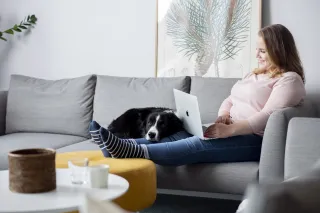 Kvinne som sitter i sofaen og jobber hjemmefra