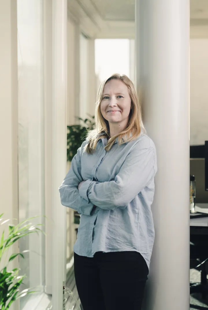 Dame som lener seg mot en stang