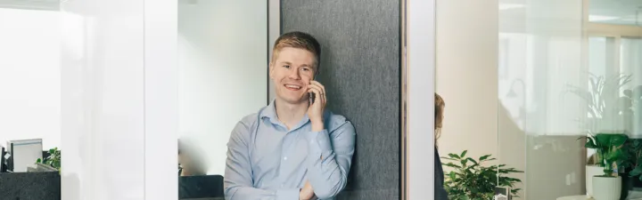 Man som prater i telefonen i en lydtett telefoncelle i åpent landskap 