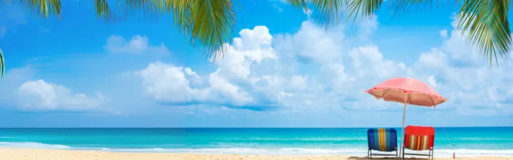 Parasol med to stoler i strandkanten 