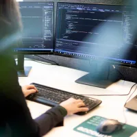 Dame som sitter foran en pc og koder