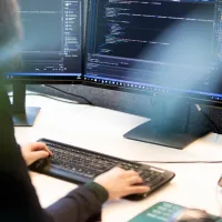 Dame som sitter foran en pc og koder