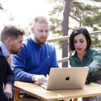 tre kolleger foran en pc