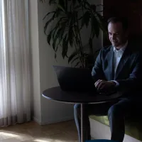 Mann med laptop sitter ved et bord og jobber