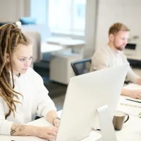 kvinne-og-mann-konsentrert-foran-hver-sin-pc