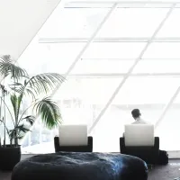 Office space with glass ceiling and a man sitting in a comfy chair with this computer