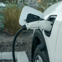 Hvit elbil på landing. man ser bare bakenden og ladekabelen plugget i